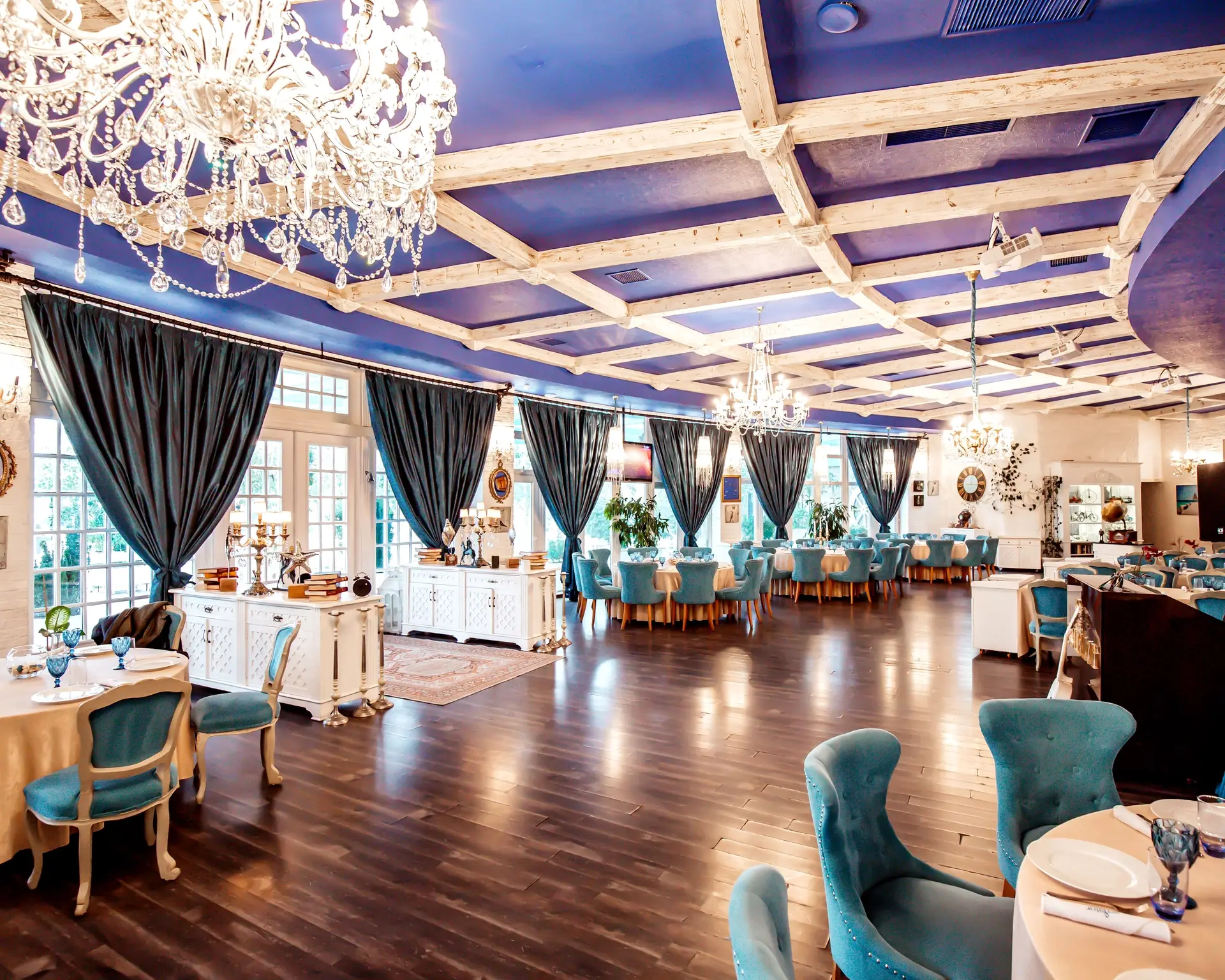 Restaurant dining room with chandeliers, coffered ceiling and upholstered seating