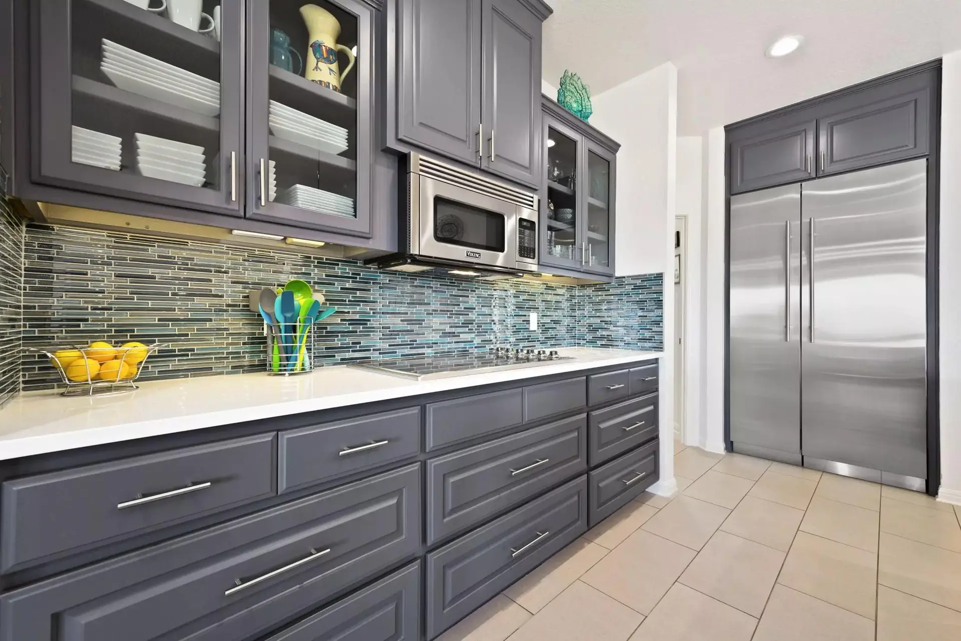 Kitchen with gray cabinetry, glass-tile backsplash and stainless steel appliances